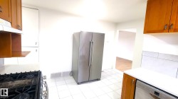 Kitchen featuring brown cabinets, stainless steel appliances, light stone counters, and under cabinet range hood - 