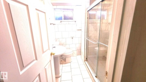 Bathroom with tile walls, a stall shower, and light tile patterned floors - 11516 133A Avenue, Edmonton, AB - Indoor Photo Showing Bathroom