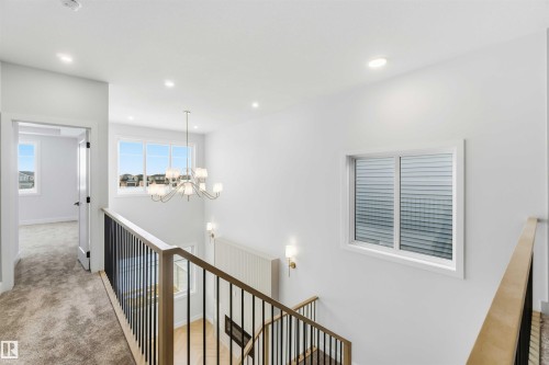 Corridor featuring an upstairs landing, suspended lighting, and light colored carpet - 94 Eldridge Pointe, St. Albert, AB - Indoor Photo Showing Other Room