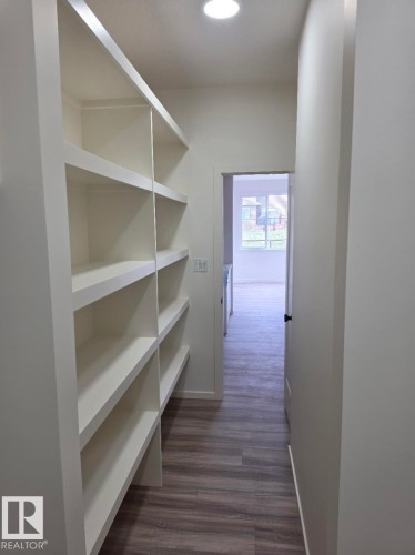 Built-in shelving with multiple levels of storage, recessed ceiling lighting, wood-finish flooring, and crisp white wall finishes - 7706 174A Avenue, Edmonton, AB - Indoor With Storage