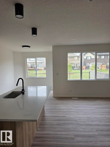Kitchen island featuring a light-toned countertop with an undermount sink and matte black gooseneck faucet - 7706 174A Avenue, Edmonton, AB - Indoor