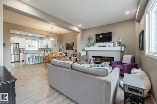 Living room featuring light wood-style flooring, a glass covered fireplace, and recessed lighting - 5 2072 Wonnacott Way, Edmonton, AB - Indoor Photo Showing Living Room With Fireplace