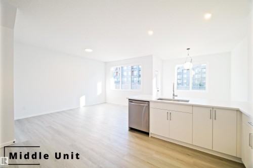 Kitchen featuring decorative light fixtures, light wood finished floors, dishwasher, modern cabinets, and open floor plan - 7585 174A Avenue, Edmonton, AB - Indoor Photo Showing Kitchen