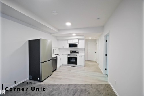 Kitchen with white cabinets, appliances with stainless steel finishes, tasteful backsplash, and light wood-style flooring - 7585 174A Avenue, Edmonton, AB - Indoor Photo Showing Kitchen