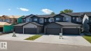 View of front facade featuring stone siding, concrete driveway, a residential view, and a garage - 7585 174A Avenue, Edmonton, AB  - Outdoor With Facade 