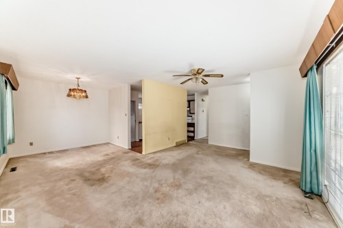 Unfurnished living room with carpet flooring, a ceiling fan, and a chandelier - Edmonton, AB - Indoor