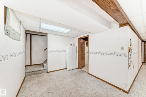 Finished below grade area with a paneled ceiling, light carpet, and stairs - Edmonton, AB - Indoor