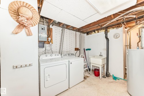 Laundry area with water heater, electric panel, separate washer and dryer, and light floors - Edmonton, AB - Indoor Photo Showing Laundry Room
