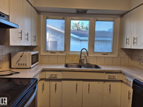 Kitchen with tasteful backsplash, white microwave, stainless steel electric range, and light countertops - 11616 152 Avenue, Edmonton, AB - Indoor Photo Showing Kitchen With Double Sink