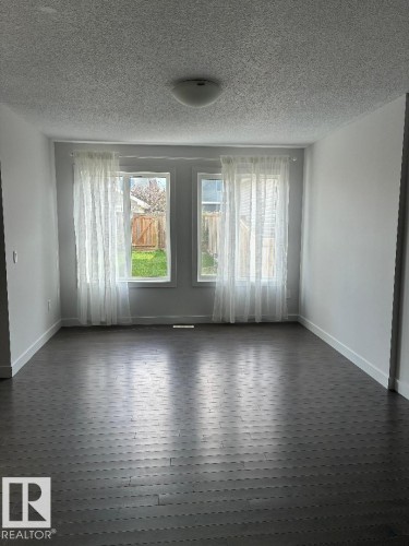 Empty room featuring a textured ceiling and dark wood-style flooring - 2433 Glenridding Boulevard, Edmonton, AB - Indoor