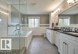 Full bath with double vanity, a shower stall, a garden tub, a wainscoted wall, and tile walls - 