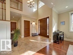 Entrance foyer featuring ornamental molding, wood finished floors, a chandelier, and a towering ceiling - 