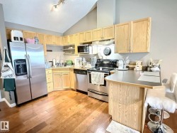 Kitchen with light brown cabinets, stainless steel appliances, high vaulted ceiling, a kitchen breakfast bar, and a peninsula - 
