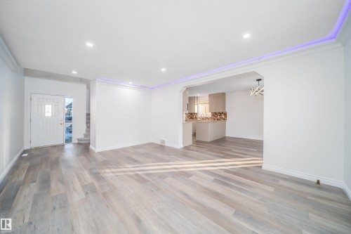 Unfurnished living room featuring light wood-type flooring, arched walkways, recessed lighting, ornamental molding, and stairway - 3504 20 Street, Edmonton, AB - Indoor Photo Showing Other Room