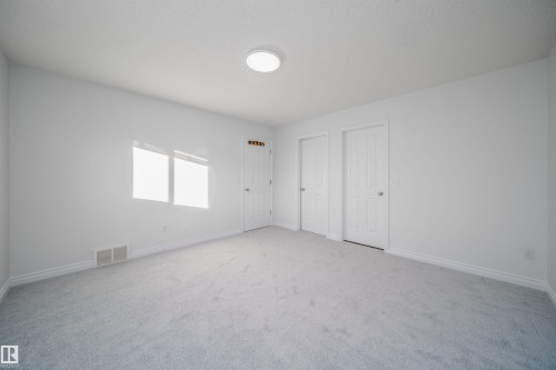 Unfurnished bedroom featuring two closets, carpet, and a textured ceiling - 3504 20 Street, Edmonton, AB - Indoor Photo Showing Other Room