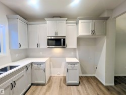 Kitchen with stainless steel microwave, tasteful backsplash, light wood finished floors, and light stone countertops - 