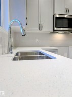 Kitchen view of white cabinetry, stainless steel microwave, and light stone countertops - 