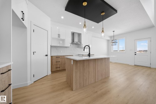Kitchen featuring dual tone cabinetry, modern cabinets, an island with sink, light wood-style flooring, and pendant lighting - 129 Pierwyck Loop, Spruce Grove, AB - Indoor Photo Showing Kitchen With Upgraded Kitchen