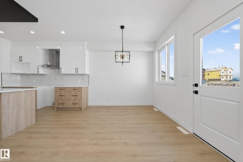 Unfurnished dining area with light wood-style floors and hanging lights - 129 Pierwyck Loop, Spruce Grove, AB - Indoor Photo Showing Kitchen
