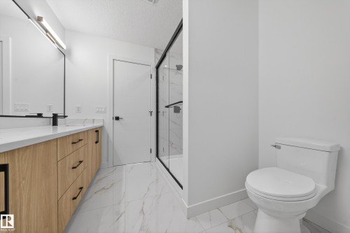 Bathroom with double vanity, a marble finish shower, light marble finish floors, and a textured ceiling - 129 Pierwyck Loop, Spruce Grove, AB - Indoor Photo Showing Bathroom