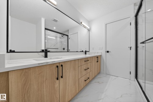 Bathroom with a marble finish shower, double vanity, light marble finish flooring, and a textured ceiling - 129 Pierwyck Loop, Spruce Grove, AB - Indoor