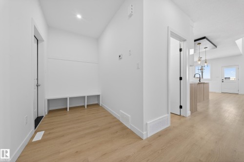 Hall featuring light wood finished floors and hanging lights - 129 Pierwyck Loop, Spruce Grove, AB - Indoor Photo Showing Other Room