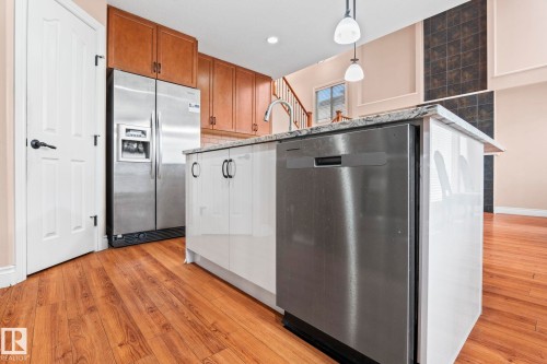 Kitchen with stainless steel appliances, pendant lighting, light stone countertops, tasteful backsplash, and light wood-type flooring - 1888 33 Street, Edmonton, AB - Indoor Photo Showing Kitchen