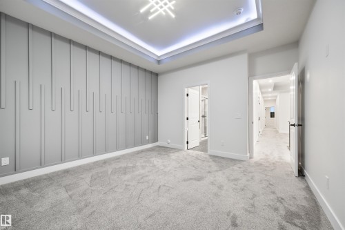Unfurnished bedroom with light colored carpet, connected bathroom, and a raised ceiling - 3164 Magpie Way, Edmonton, AB - Indoor Photo Showing Other Room