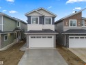 View of front facade with board and batten siding, driveway, a garage, a shingled roof, and brick siding - 3164 Magpie Way, Edmonton, AB  - Outdoor With Facade 