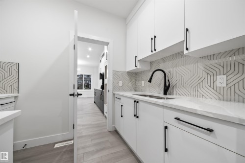 Kitchen featuring white cabinets, light stone counters, and light wood-style flooring - 3164 Magpie Way, Edmonton, AB - Indoor Photo Showing Kitchen With Double Sink