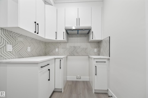 Kitchen featuring white cabinets, modern cabinets, light wood finished floors, and under cabinet range hood - 3164 Magpie Way, Edmonton, AB - Indoor Photo Showing Kitchen