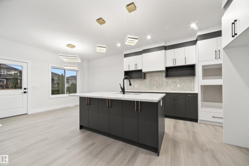 Kitchen featuring white cabinetry, pendant lighting, backsplash, a center island with sink, and light wood finished floors - 3164 Magpie Way, Edmonton, AB - Indoor Photo Showing Kitchen With Upgraded Kitchen