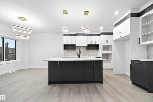 Kitchen with white cabinetry, pendant lighting, tasteful backsplash, an island with sink, and light wood-style floors - 3164 Magpie Way, Edmonton, AB - Indoor Photo Showing Kitchen