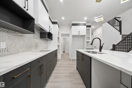 Kitchen featuring open shelves, white cabinetry, dark cabinets, light stone countertops, and recessed lighting - 3164 Magpie Way, Edmonton, AB - Indoor Photo Showing Kitchen With Double Sink