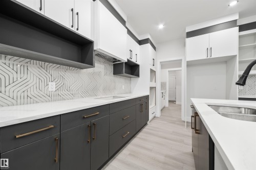 Kitchen featuring open shelves, white cabinets, tasteful backsplash, light wood-type flooring, and light stone counters - 3164 Magpie Way, Edmonton, AB - Indoor Photo Showing Kitchen With Double Sink
