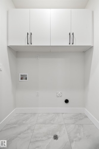 Washroom featuring cabinet space, washer hookup, and light marble finish flooring - 3164 Magpie Way, Edmonton, AB - Indoor