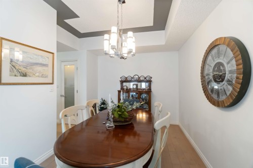 Dining space featuring a chandelier, light wood finished floors, and a tray ceiling - 1101 9020 Jasper Avenue, Edmonton, AB - Indoor Photo Showing Dining Room