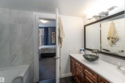 Ensuite bathroom with vanity, a tub to relax in, and dark tile patterned flooring - 