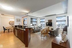 Kitchen featuring open floor plan, dark stone countertops, track lighting, a fireplace, and dark brown cabinets - 