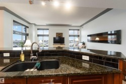 Kitchen with open floor plan, dark stone countertops, rail lighting, plenty of natural light, and a textured ceiling - 