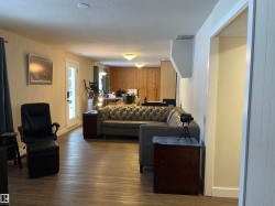 Living area with dark wood-style floors, wooden walls, a textured ceiling, and a desk - 
