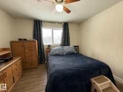 Bedroom featuring a ceiling fan, a textured ceiling, and dark wood-type flooring - 