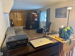 Living area with wood walls, wood finished floors, and a fireplace - 