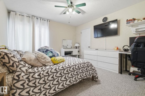 Carpeted bedroom featuring a textured ceiling, a ceiling fan, and an office area - 205 11440 40 Ave, Edmonton, AB - Indoor Photo Showing Bedroom