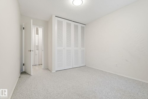 Unfurnished bedroom with a closet, carpet flooring, and a textured ceiling - 205 11440 40 Ave, Edmonton, AB - Indoor Photo Showing Other Room