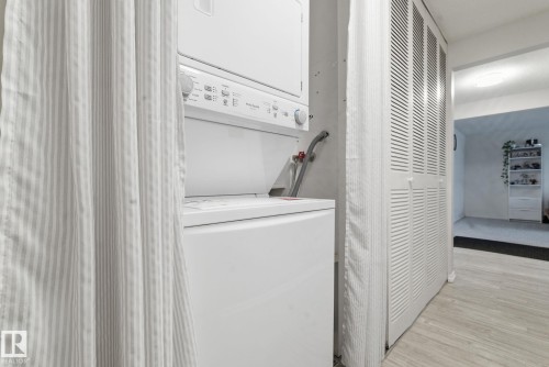 Laundry room with stacked washer / dryer and light wood-style floors - 205 11440 40 Ave, Edmonton, AB - Indoor Photo Showing Laundry Room