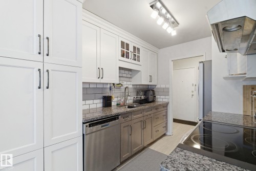 Kitchen with exhaust hood, glass insert cabinets, stainless steel appliances, white cabinetry, and backsplash - 205 11440 40 Ave, Edmonton, AB - Indoor Photo Showing Kitchen