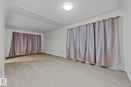 Empty room featuring a textured ceiling and light wood-style flooring - Edmonton, AB - Indoor Photo Showing Other Room