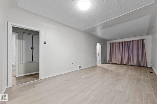 Unfurnished living room with arched walkways, a textured ceiling, and light wood finished floors - Edmonton, AB - Indoor Photo Showing Other Room
