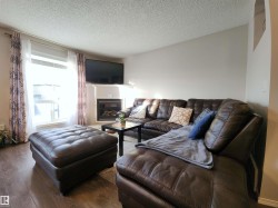 Living area with a textured ceiling, a glass covered fireplace, and hardwood / wood-style flooring - 